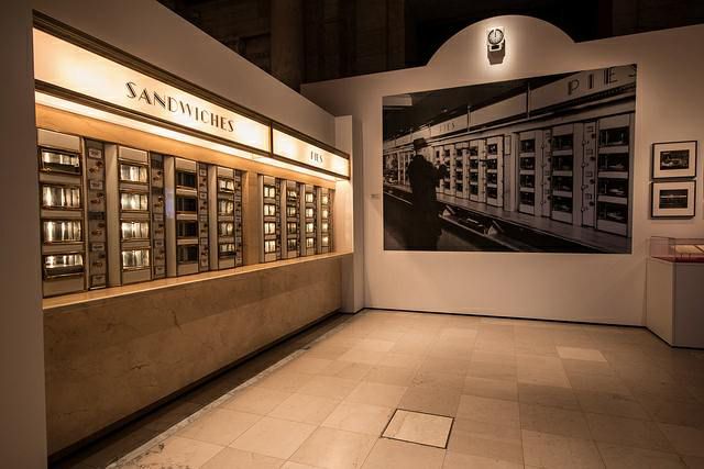 Restored Automat machines, along with a Berenice Abbott photograph of an Automat in 1937. Now instead of food the Automat has recipes.